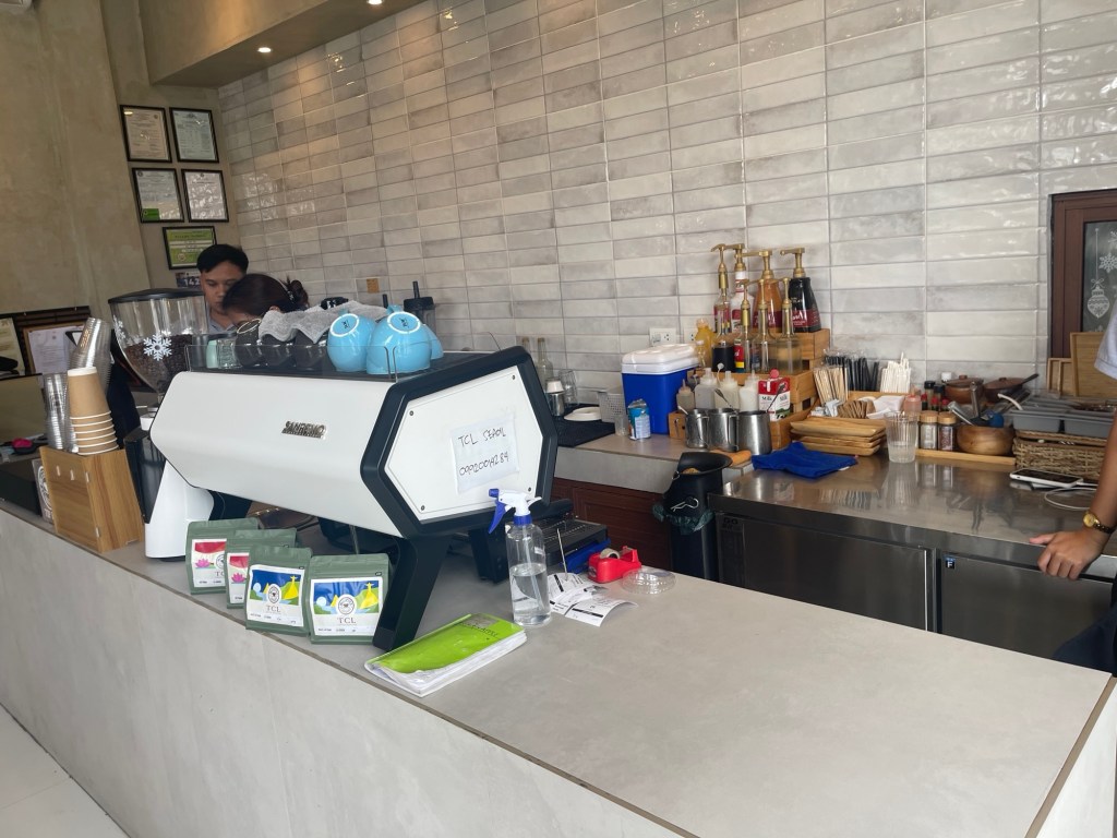 The Coffee Library counter featuring a modern espresso machine, various coffee supplies, and a bartender preparing drinks.
