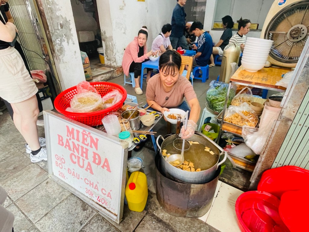     The lady cooking orders beside a large pot and frying dough